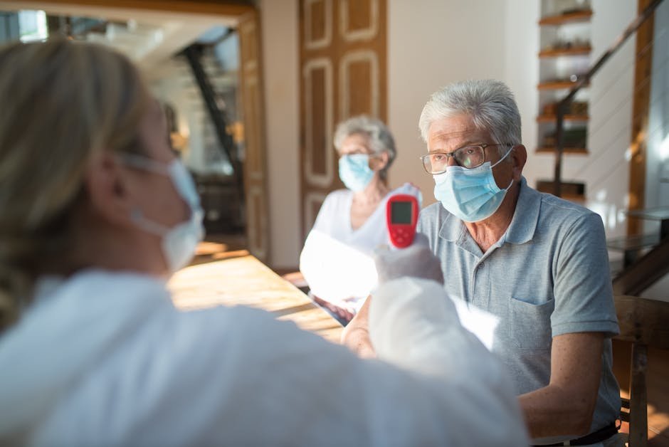 Healthcare worker checks temperature of senior adults during pandemic using a thermometer in a home setting.