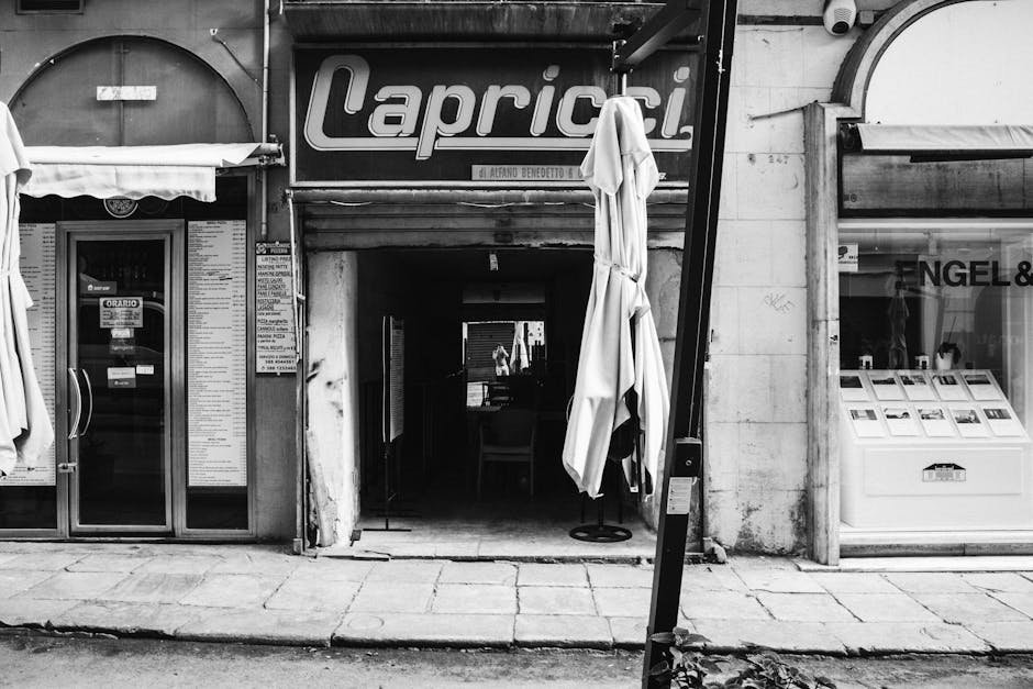 Vintage black and white photo of a street scene in Palermo, Sicily, capturing local storefronts.